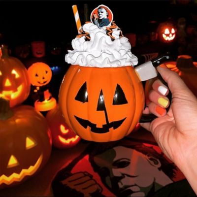 Pumpkin mug with knife handle topped with whipped cream and straw and Michael Myers topper
