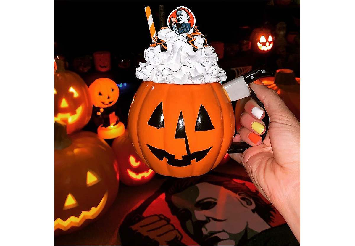 Pumpkin mug with knife handle topped with whipped cream and straw and Michael Myers topper