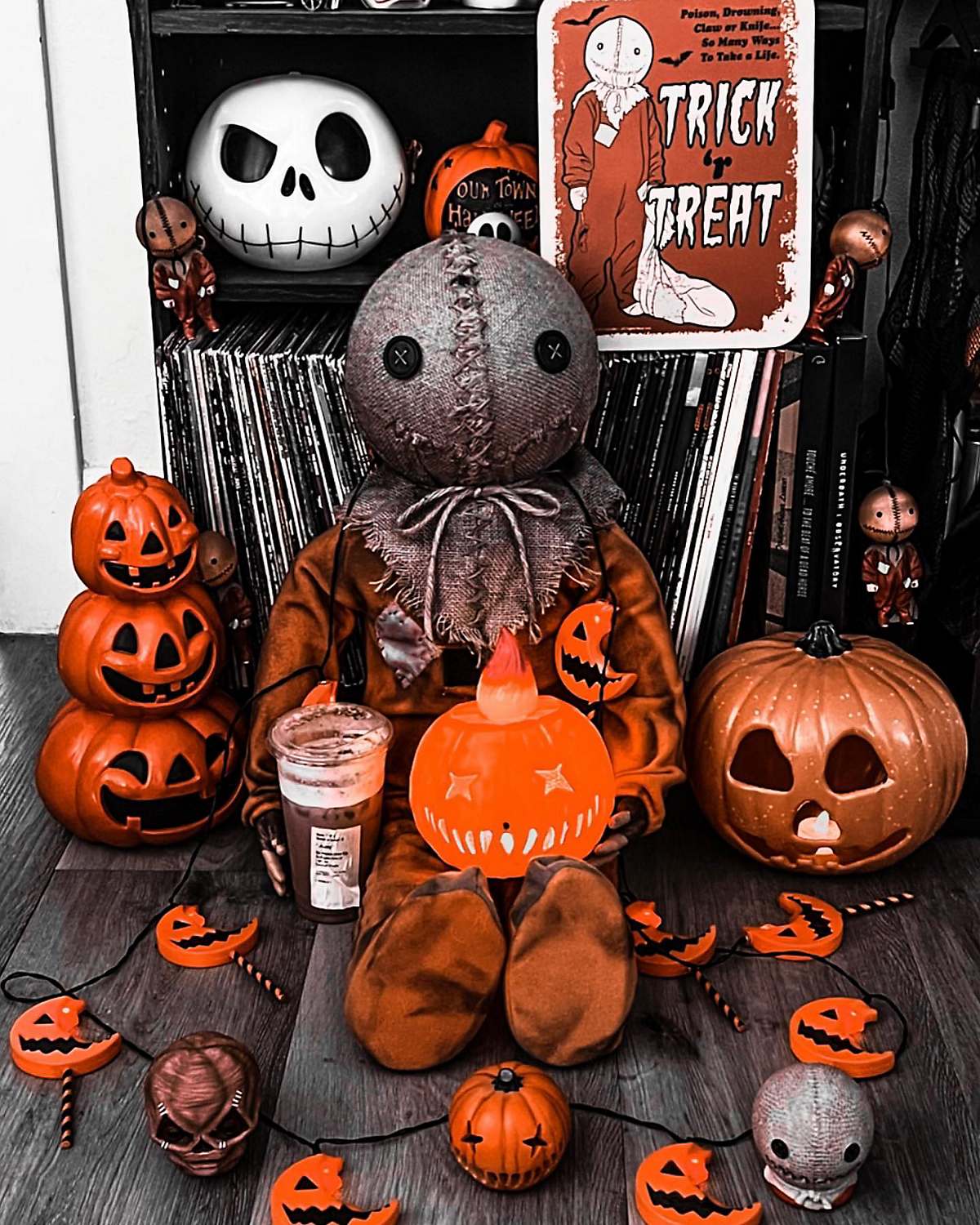 Sam from Trick 'r Treat figure surrounded by pumpkins and half-eaten lollipops with Jack Skellington toy on shelf behind him