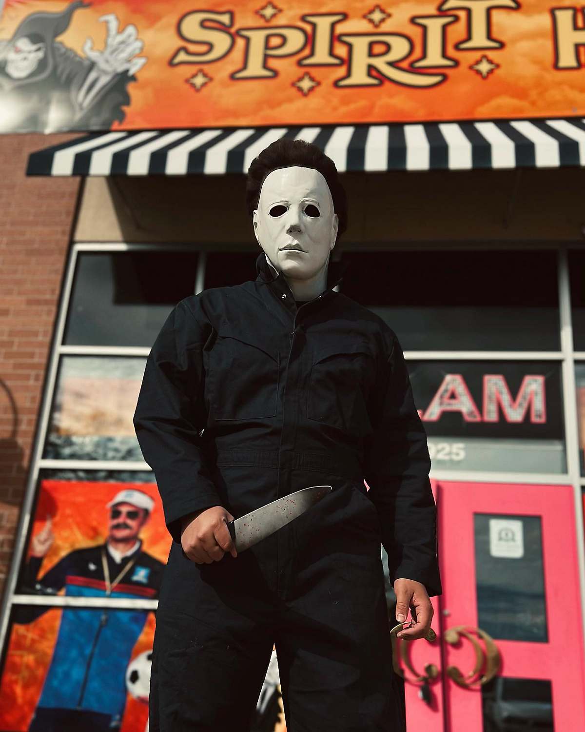 Person dressed as Michael Myers from Halloween in front of Spirit Halloween store
